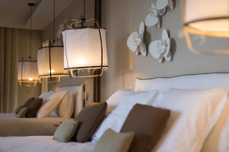 Lits préparés avec oreillers et luminaires décoratifs.