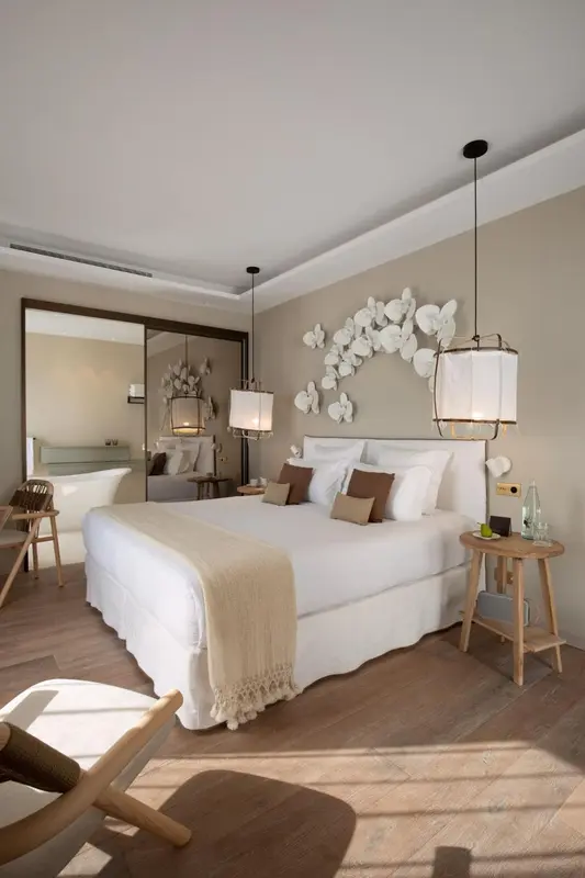 Une chambre lumineuse avec un grand lit recouvert d'une couverture beige et de coussins.