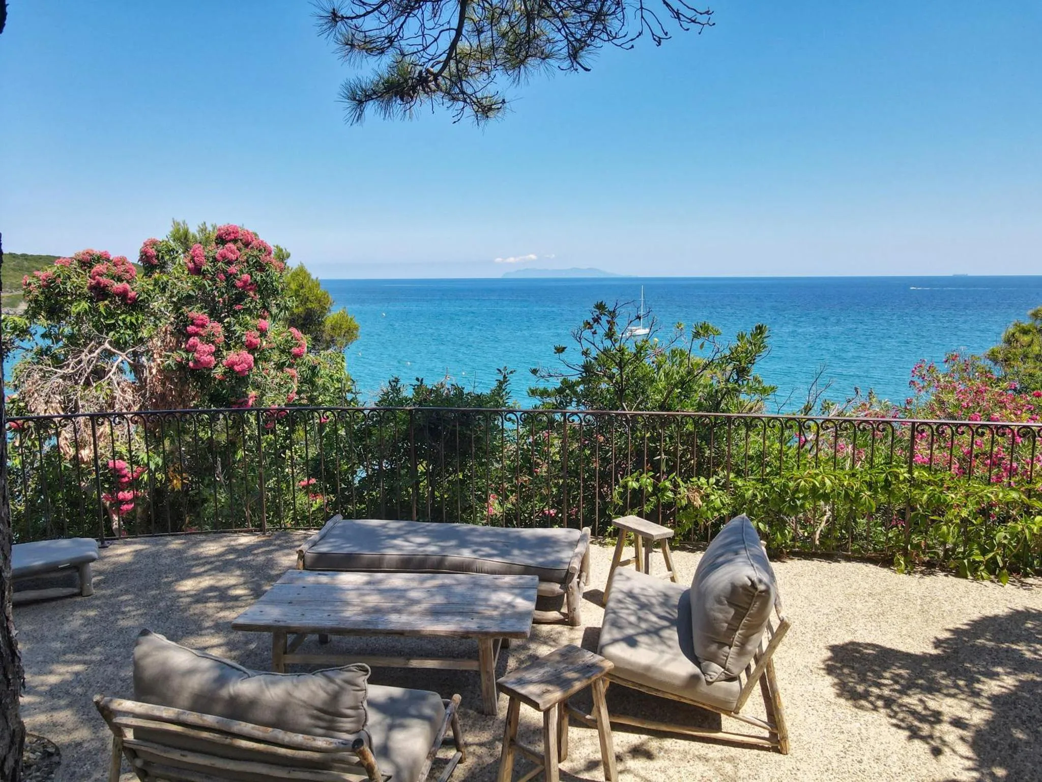 Terrasse avec mobilier de jardin et vue sur la mer.