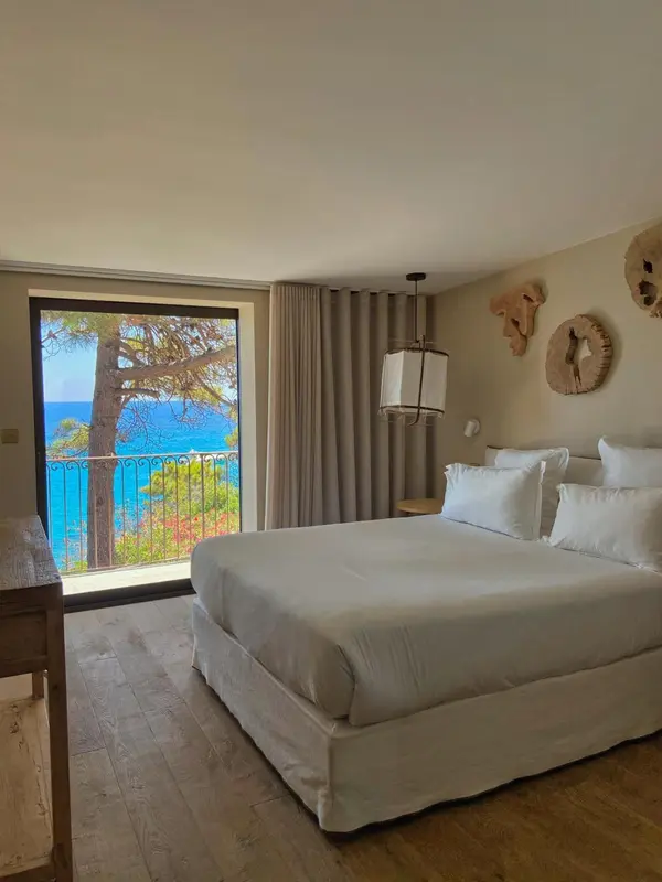 Une chambre lumineuse avec un grand lit donnant sur une vue mer.