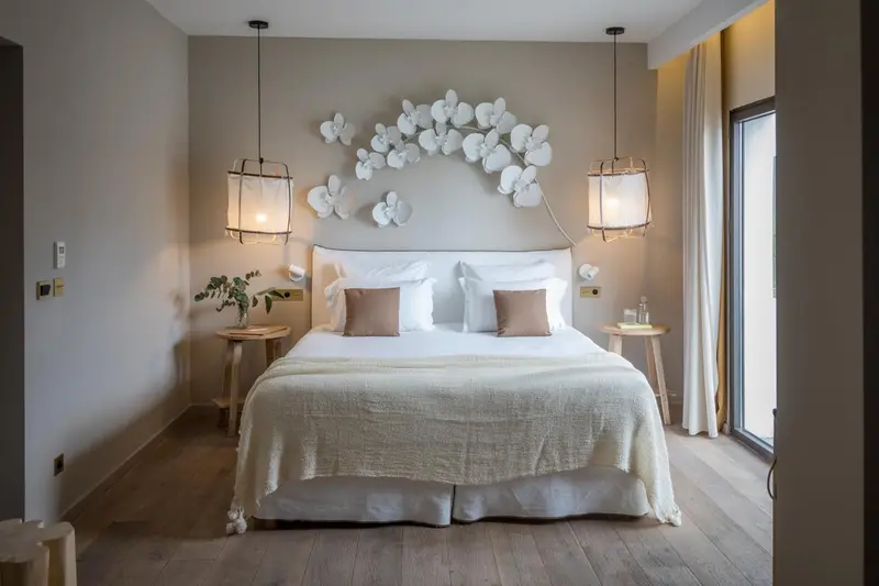 Une chambre lumineuse avec un grand lit recouvert d'une couverture blanche et de coussins.
