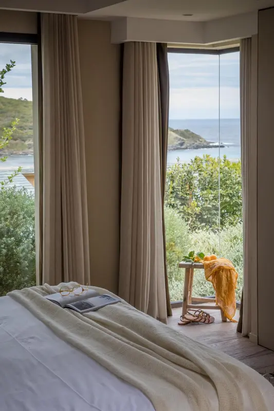 Une chambre lumineuse avec vue sur la mer à travers de larges baies vitrées.