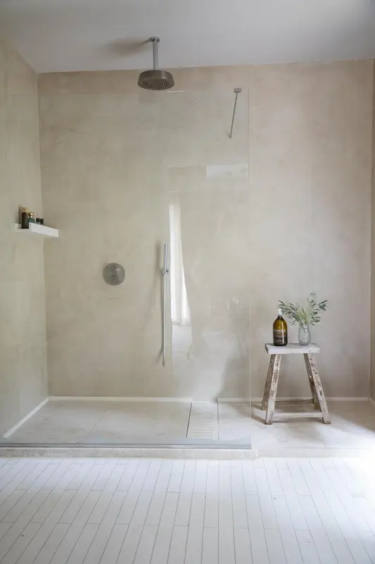 Une douche à l'italienne minimaliste avec un sol carrelé clair et un mur texturé.