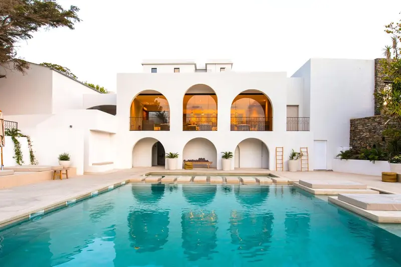 Vue d'une piscine devant un bâtiment blanc aux arches.