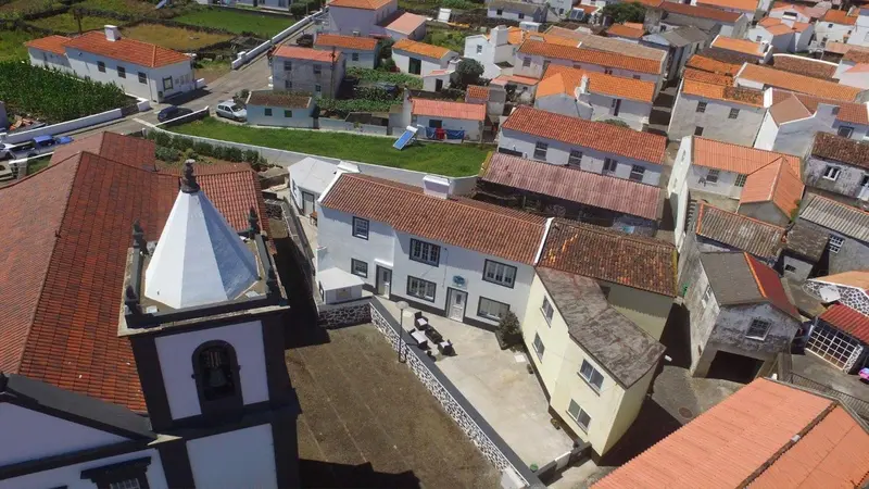 Vue aérienne d'un village avec des maisons aux toits rouges et une église.