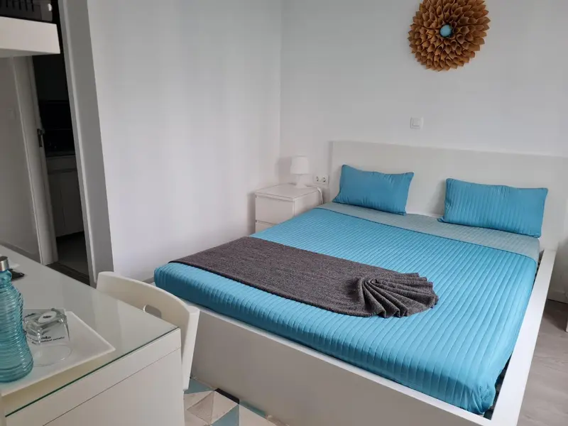 Une chambre lumineuse avec un lit recouvert d'une courtepointe bleue et turquoise.