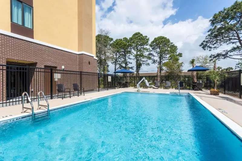 Une piscine rectangulaire avec des transats et des parasols bleus.