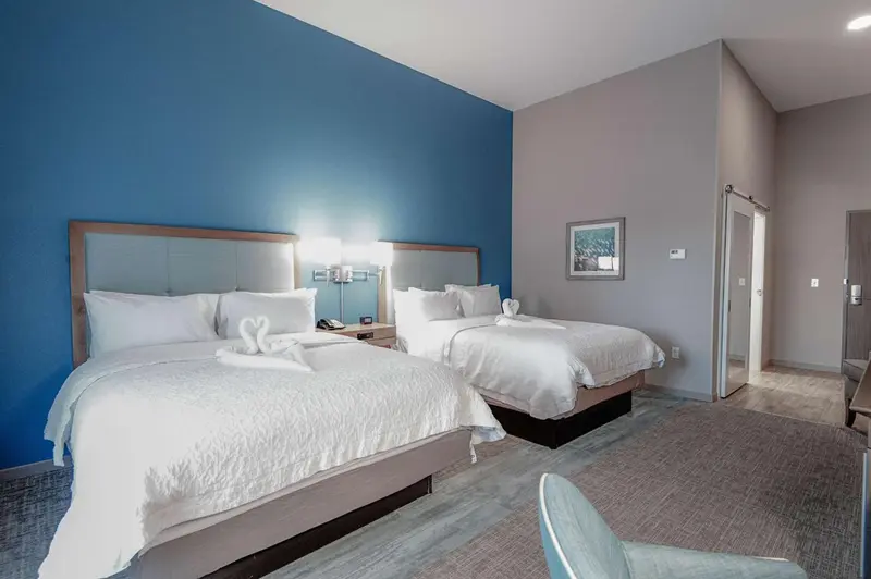 Deux lits doubles dans une chambre lumineuse avec un mur bleu.