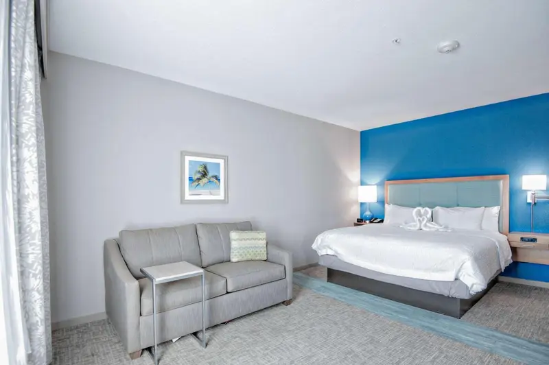 Une chambre lumineuse avec un canapé et un grand lit décoré de serviettes en forme de cygnes.