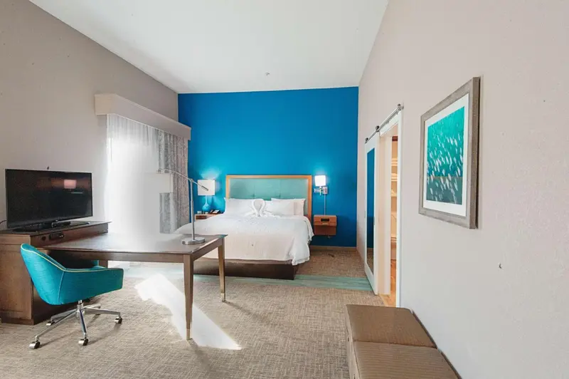 Une chambre lumineuse avec un grand lit et un espace bureau.