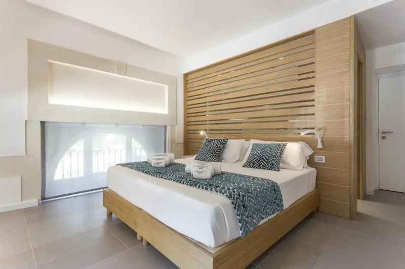 Une chambre lumineuse avec un grand lit recouvert d'une courtepointe bleue et de coussins.