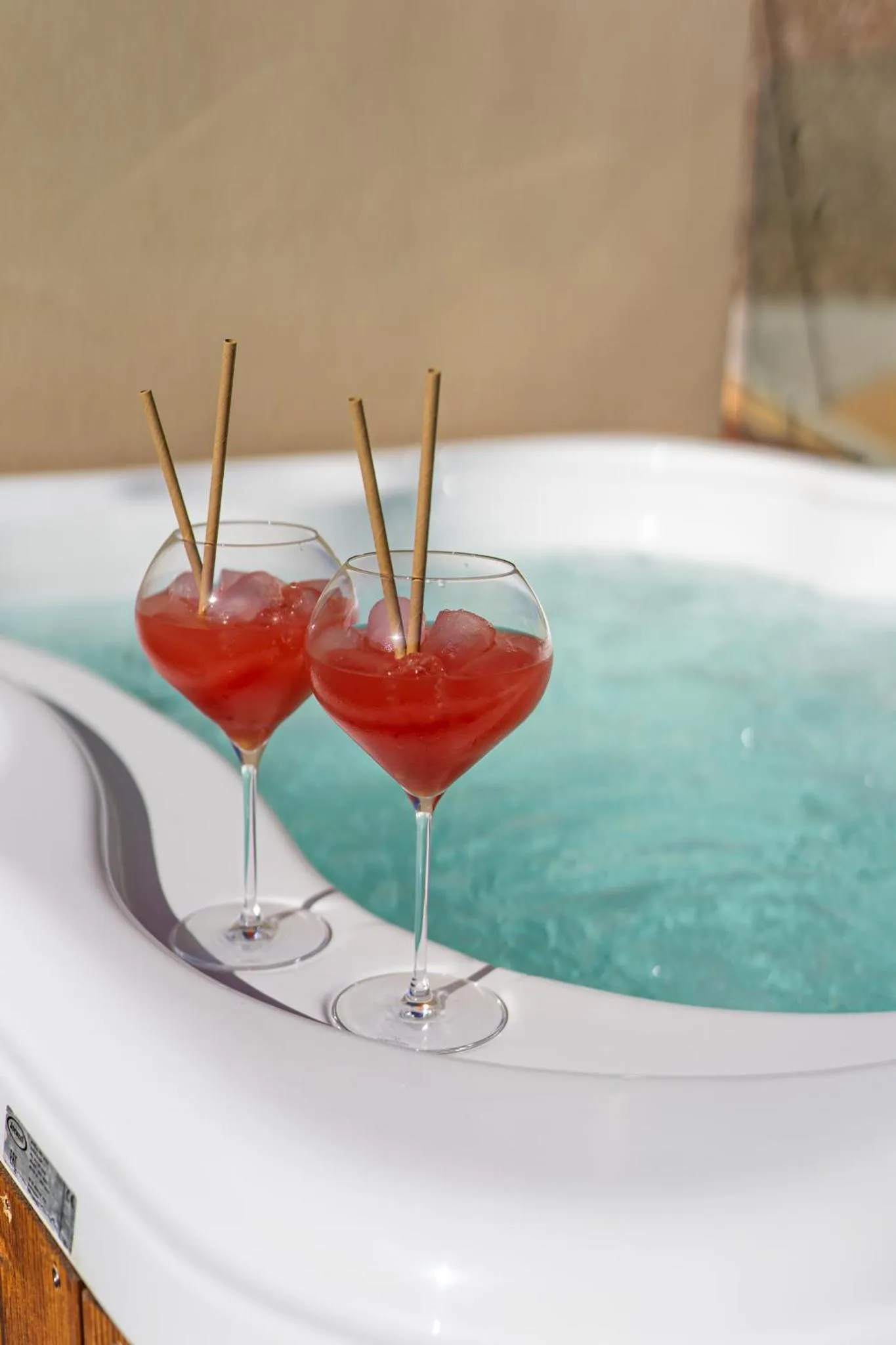 Deux verres de cocktail colorés reposent sur le bord d'un jacuzzi.