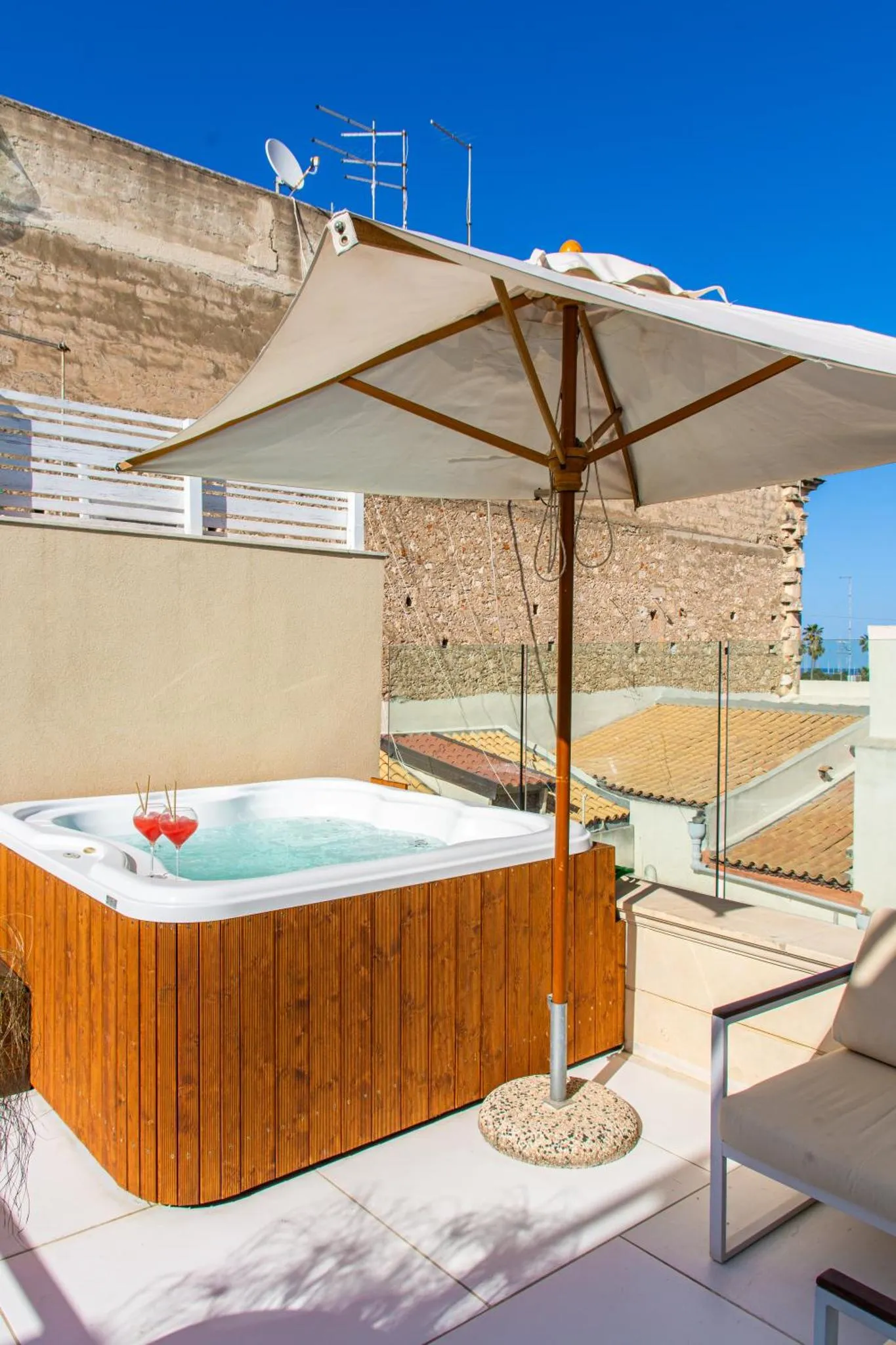 Un jacuzzi extérieur avec des boissons sur une terrasse ensoleillée.