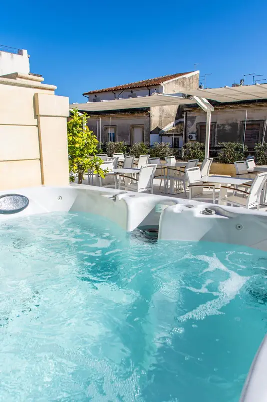 Jacuzzi extérieur avec transats et végétation luxuriante.