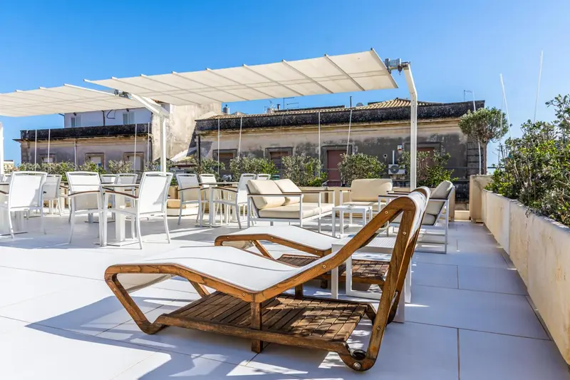 Terrasse aménagée avec transats et parasols blancs.