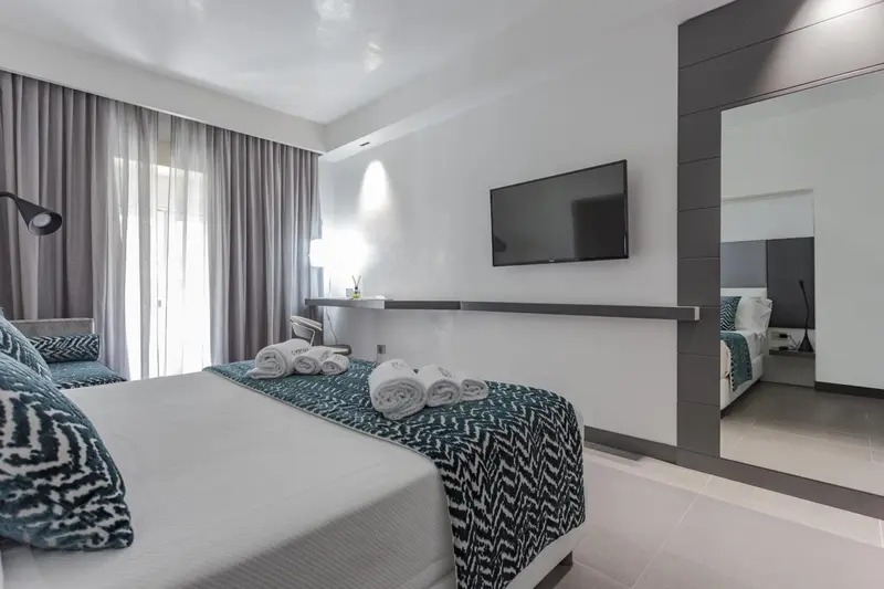 Une chambre lumineuse avec un grand lit et un téléviseur mural.