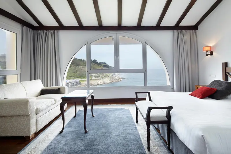 Une chambre lumineuse avec un canapé et un lit donnant sur une vue mer.