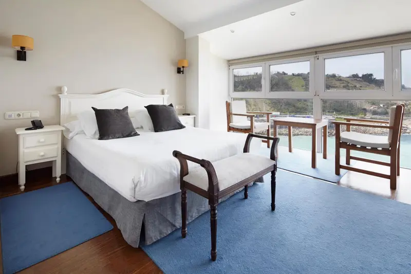 Chambre lumineuse avec un grand lit et vue sur la mer.