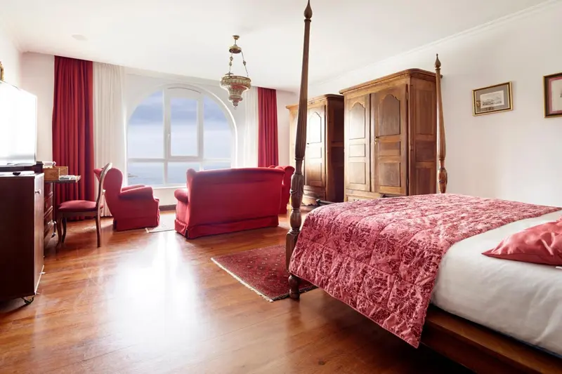 Une chambre spacieuse avec un grand lit à baldaquin et un coin salon.