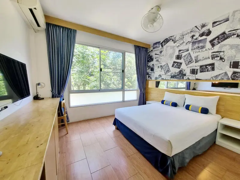 Une chambre lumineuse avec un lit double et un bureau près de la fenêtre.