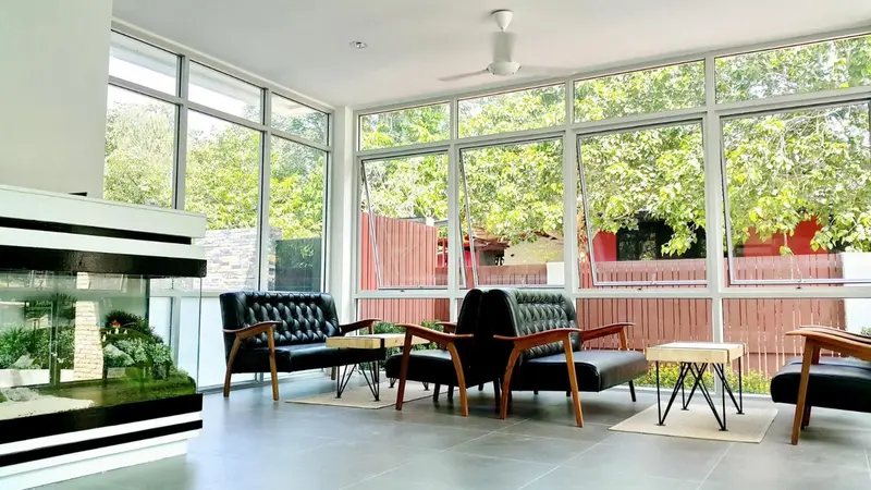 Espace de détente lumineux avec canapés et fauteuils face à une grande baie vitrée.