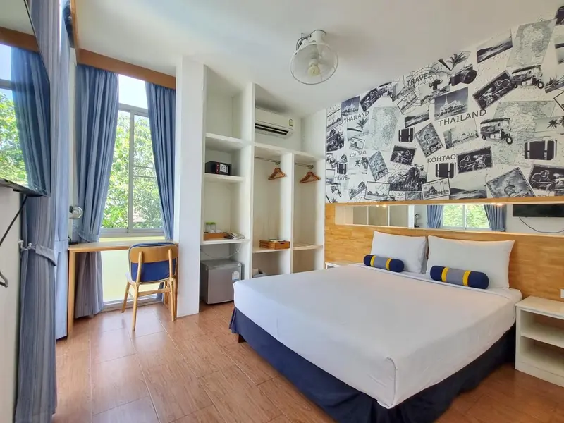 Chambre lumineuse avec un lit double et un bureau près d'une fenêtre.