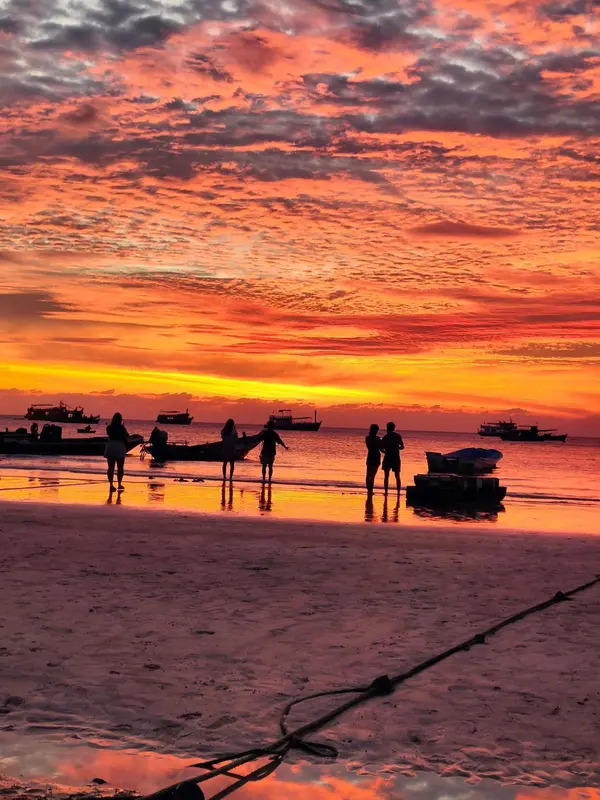 Silhouette de personnes sur une plage au coucher du soleil.