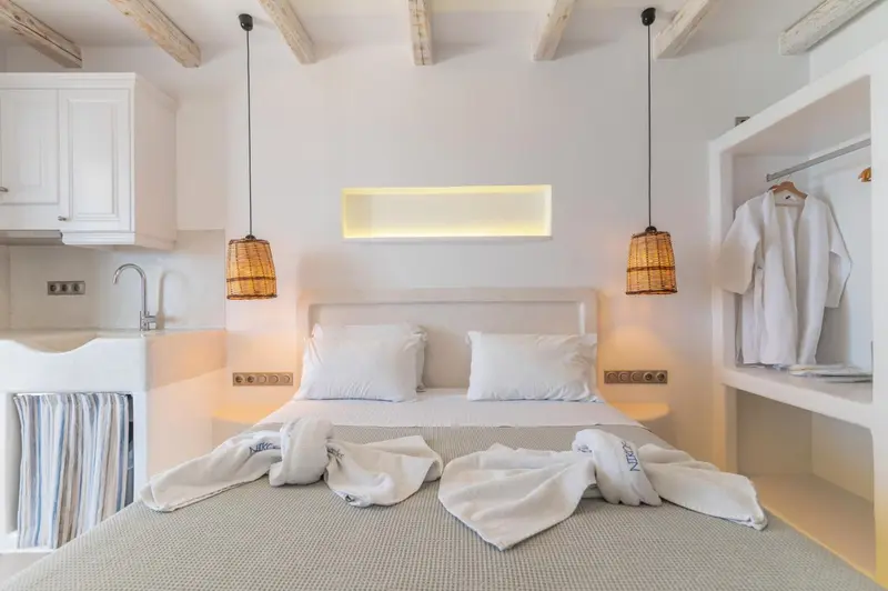 Une chambre lumineuse avec un lit double et un coin cuisine.