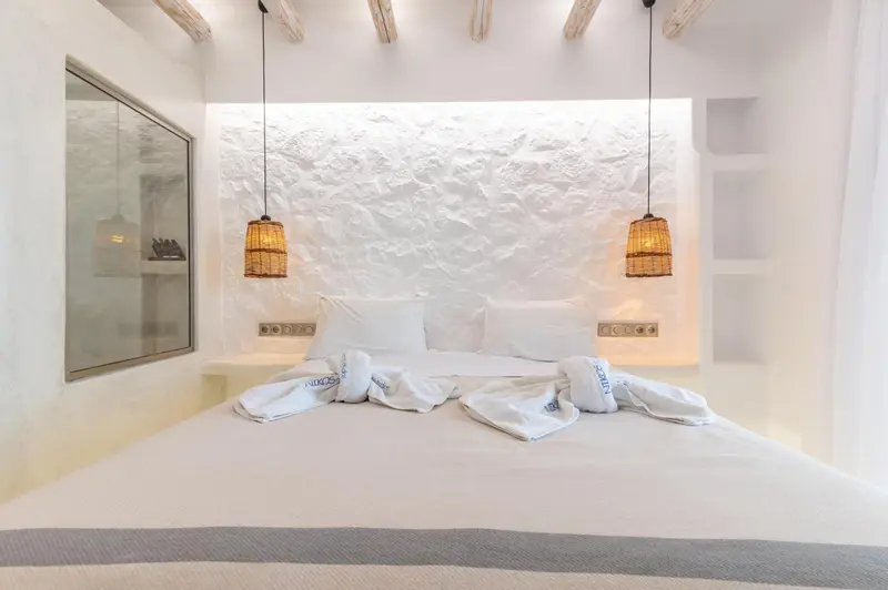 Lit double avec oreillers blancs dans une chambre au style minimaliste.