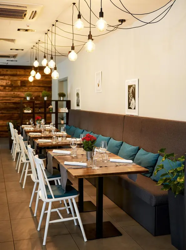 Une salle de restaurant lumineuse avec des tables en bois et des banquettes turquoise.