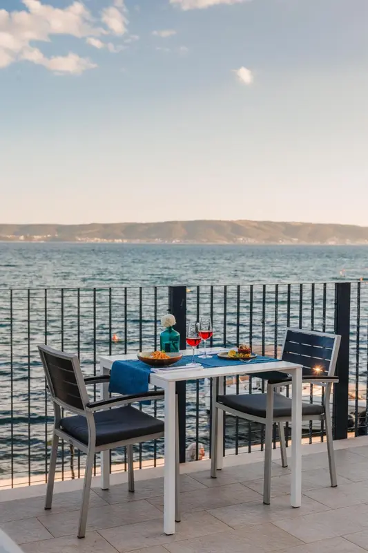 Une table est dressée sur une terrasse avec vue sur la mer.