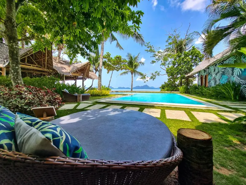 Espace de détente extérieur avec mobilier et piscine bordée de végétation.