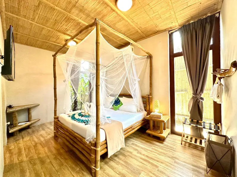 Une chambre avec un lit à baldaquin en bambou et une décoration tropicale.