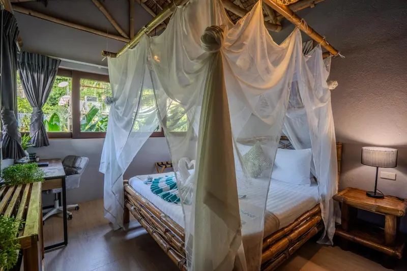 Une chambre avec un lit à baldaquin et une décoration en bambou.