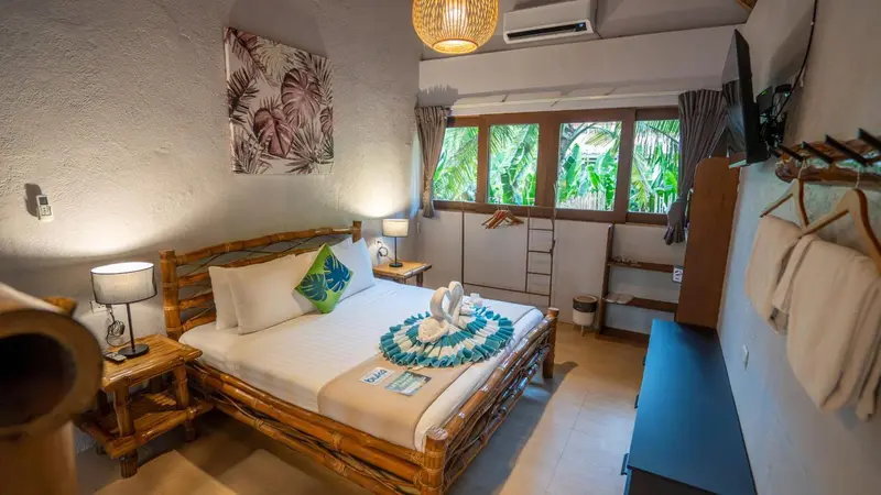 Une chambre lumineuse avec un lit en bois et une décoration tropicale.