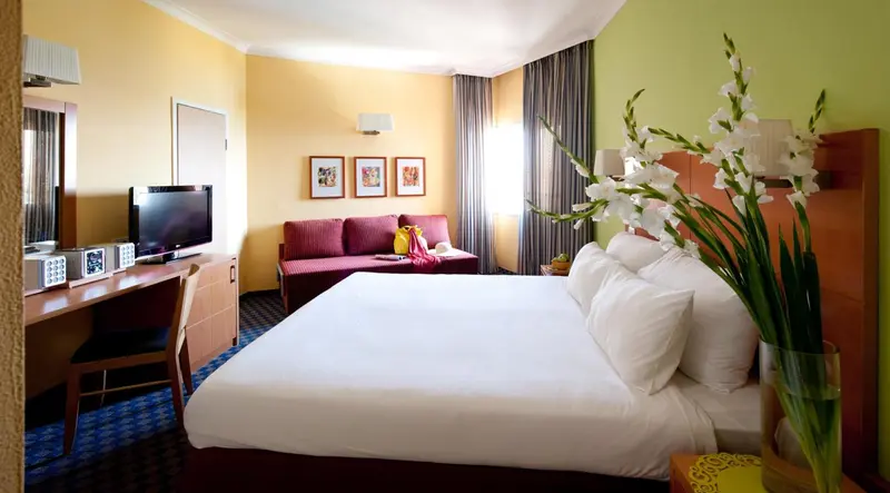Une chambre lumineuse avec un lit double et un coin salon.