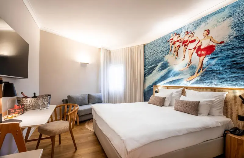 Une chambre lumineuse avec un grand lit et un mur décoré d'une fresque marine.
