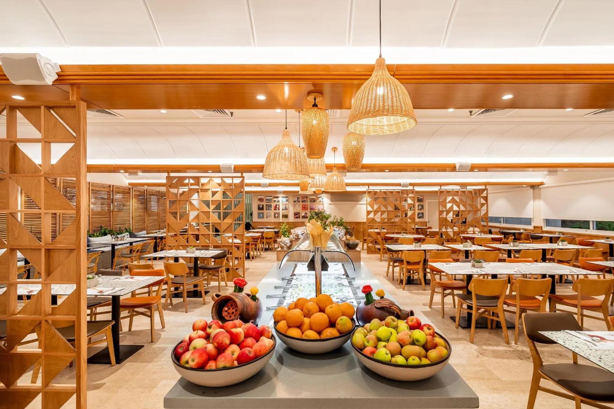 Une salle lumineuse avec des tables et des chaises, un buffet de fruits frais en premier plan.