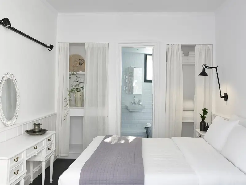 Une chambre lumineuse avec un lit recouvert d'une courtepointe et un accès à une salle de bain.