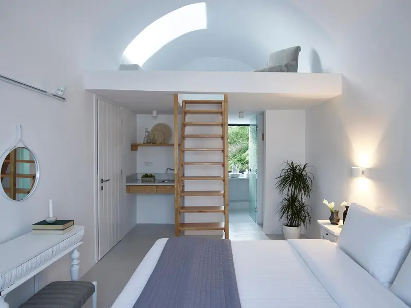 Une chambre lumineuse avec un lit et un accès à une mezzanine par un escalier en bois.
