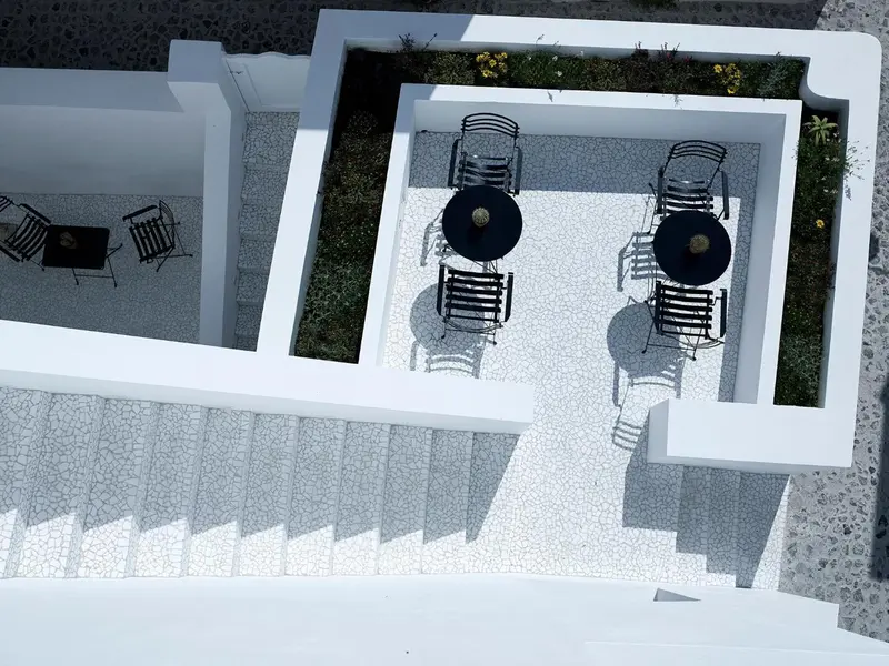 Terrasse aménagée avec tables et chaises noires sur un sol clair.