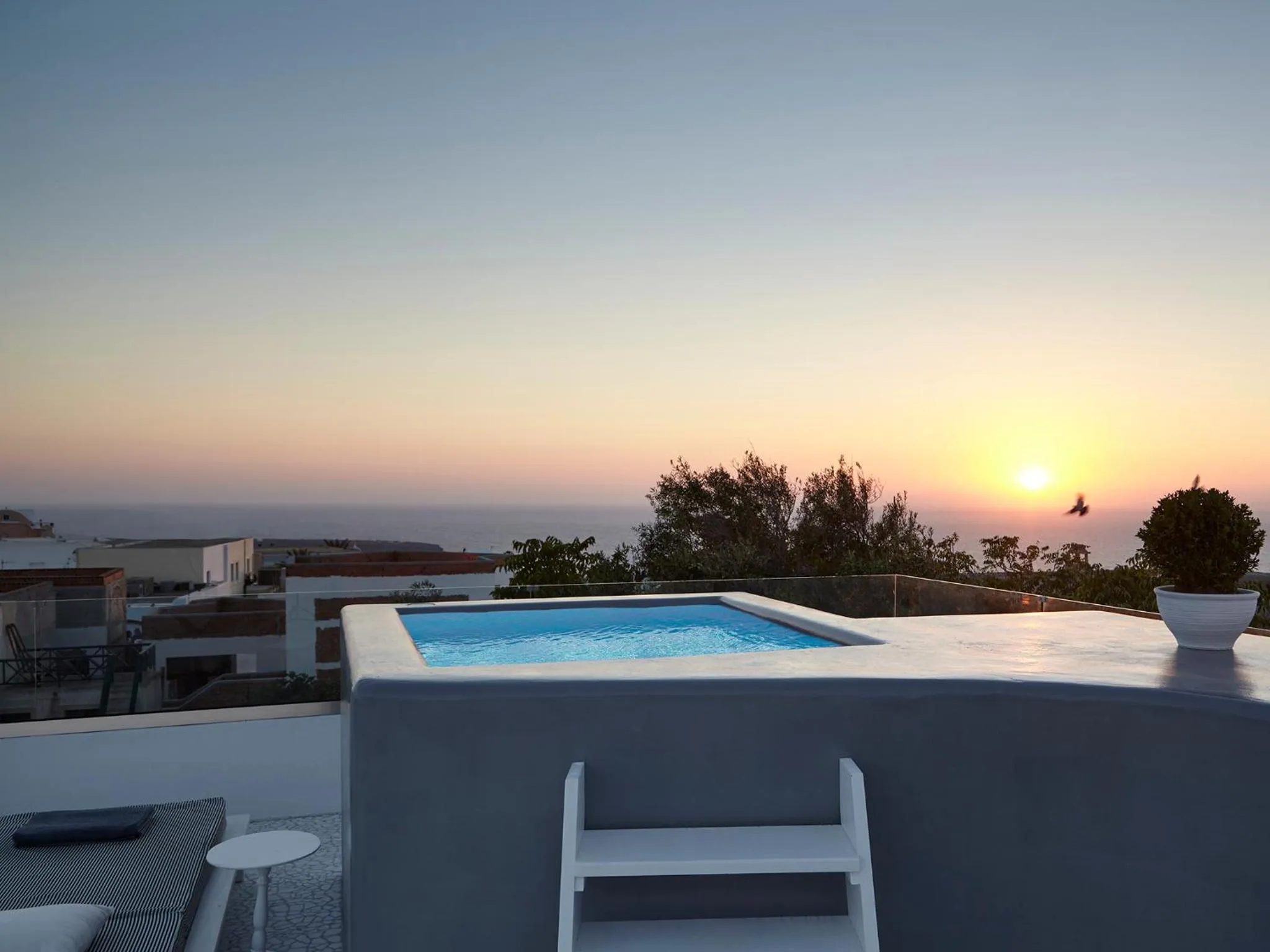 Une petite piscine sur une terrasse avec vue sur la mer au coucher du soleil.
