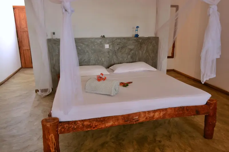 Une chambre lumineuse avec un grand lit recouvert de moustiquaire.