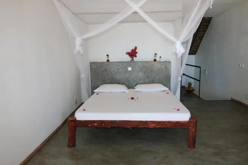 Une chambre lumineuse avec un lit à baldaquin décoré de pétales de fleurs.