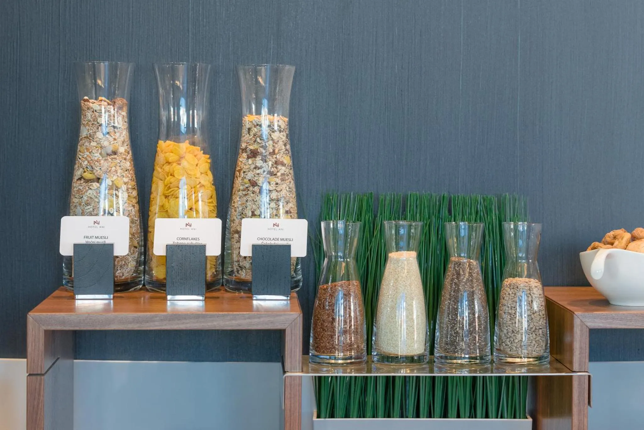 Des bocaux en verre remplis de céréales et de fruits secs sont disposés sur un comptoir en bois.