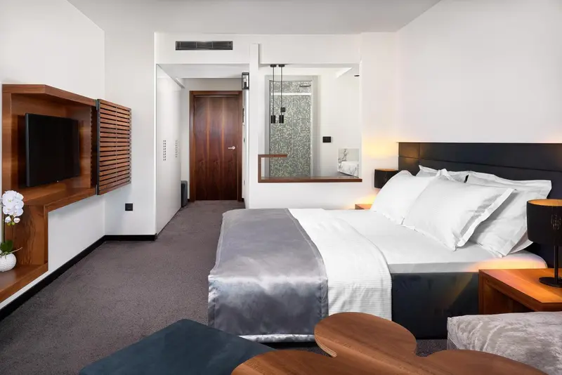 Une chambre moderne avec un grand lit et une télévision murale.
