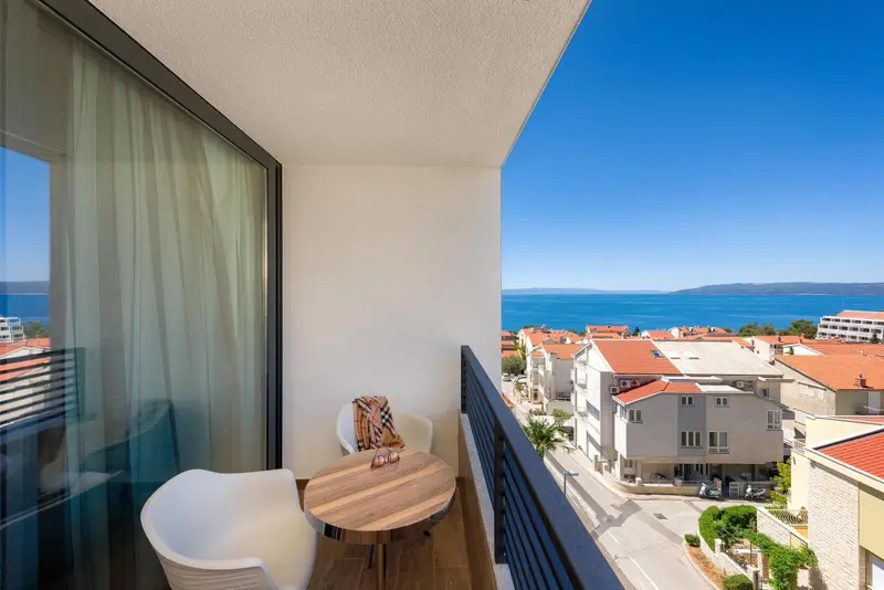 Balcon avec mobilier de jardin donnant sur une vue urbaine et la mer.