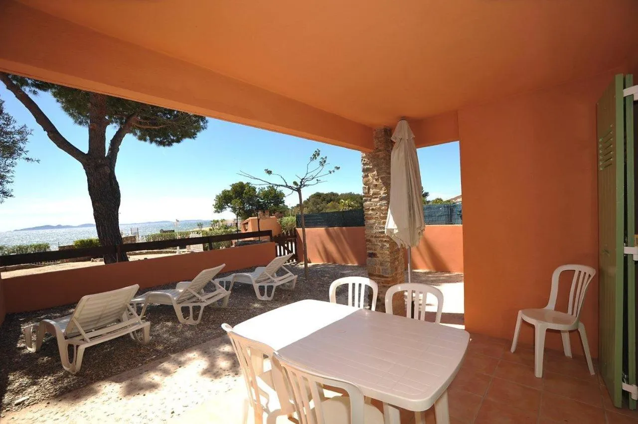 Terrasse ombragée avec mobilier de jardin et vue sur la mer.