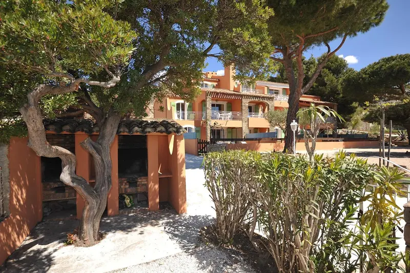 Bâtiment orange avec des balcons et des arbres verts en premier plan.