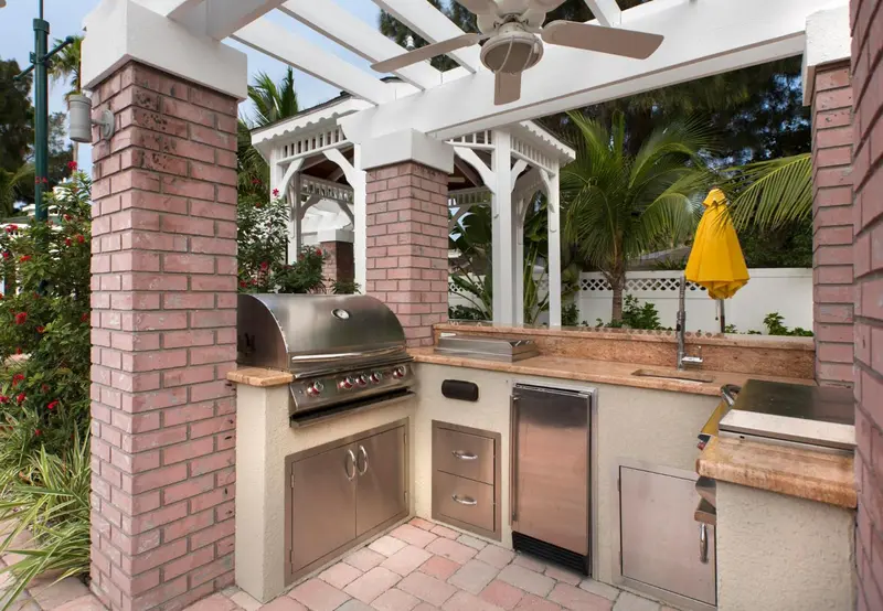 Un espace extérieur aménagé avec un barbecue encastré et un coin repas ombragé.